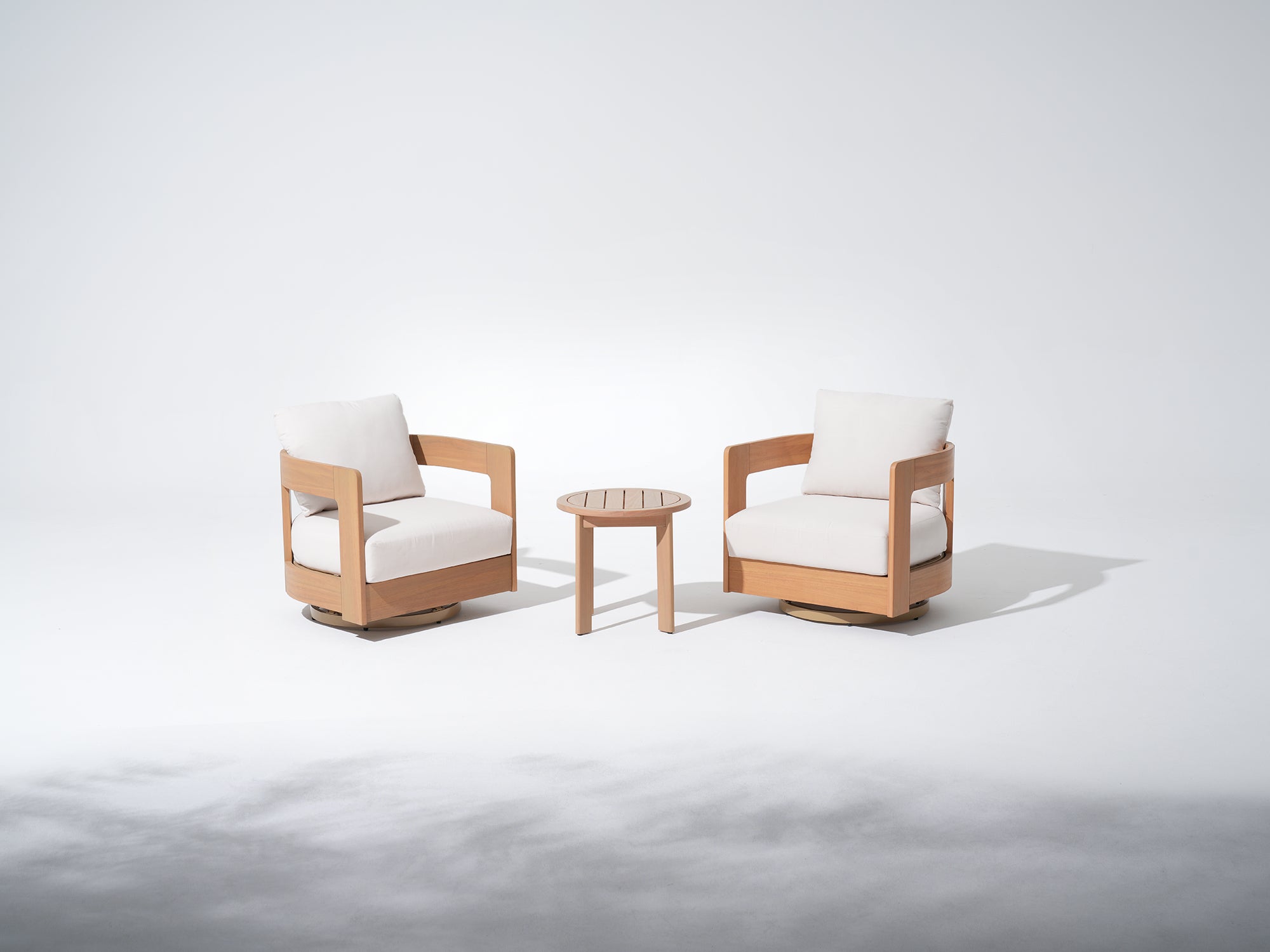 Two wooden swivel chairs with white cushions and a small round coffee table