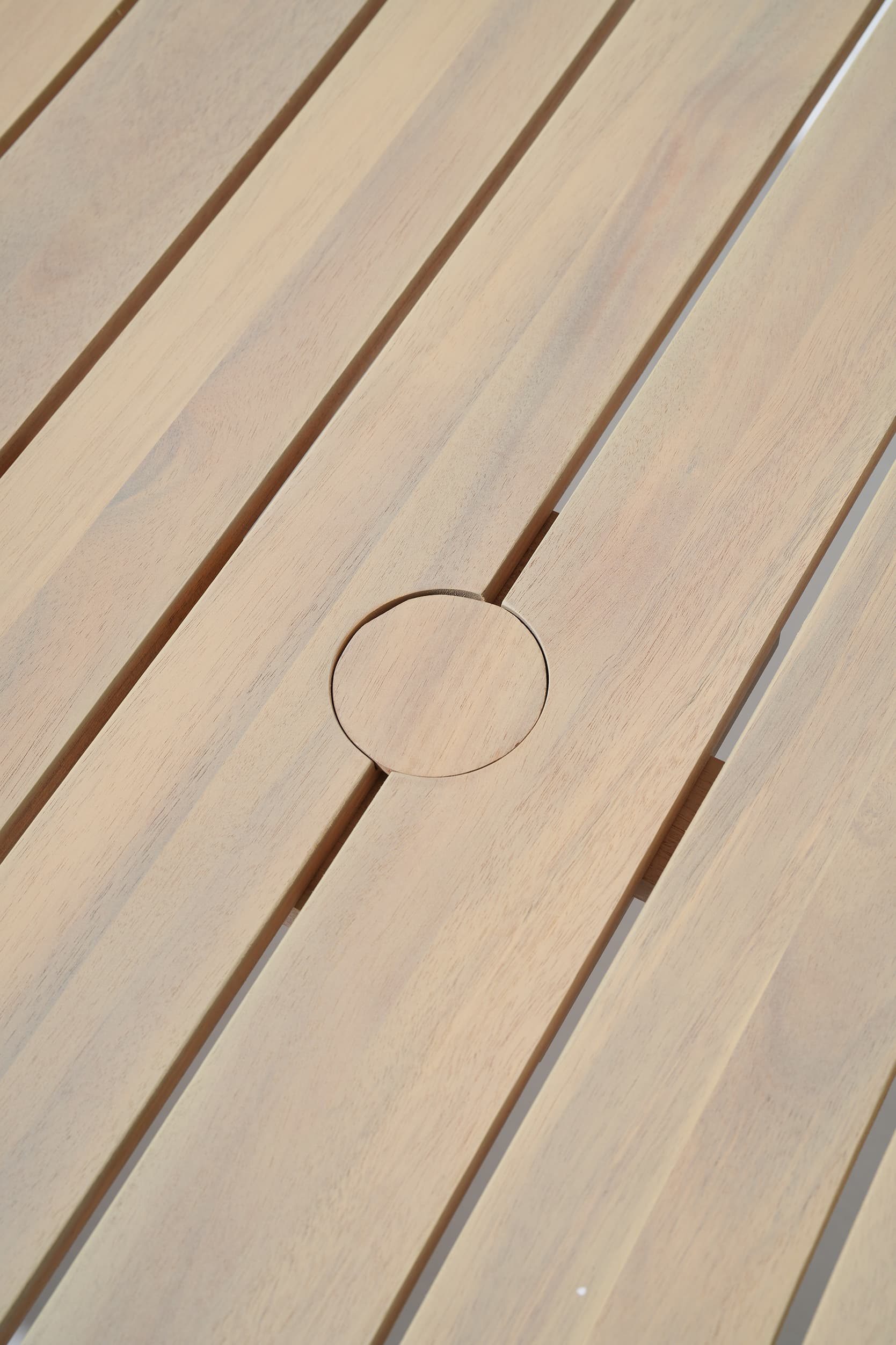 Close-up of wooden slats table with a circular hole
