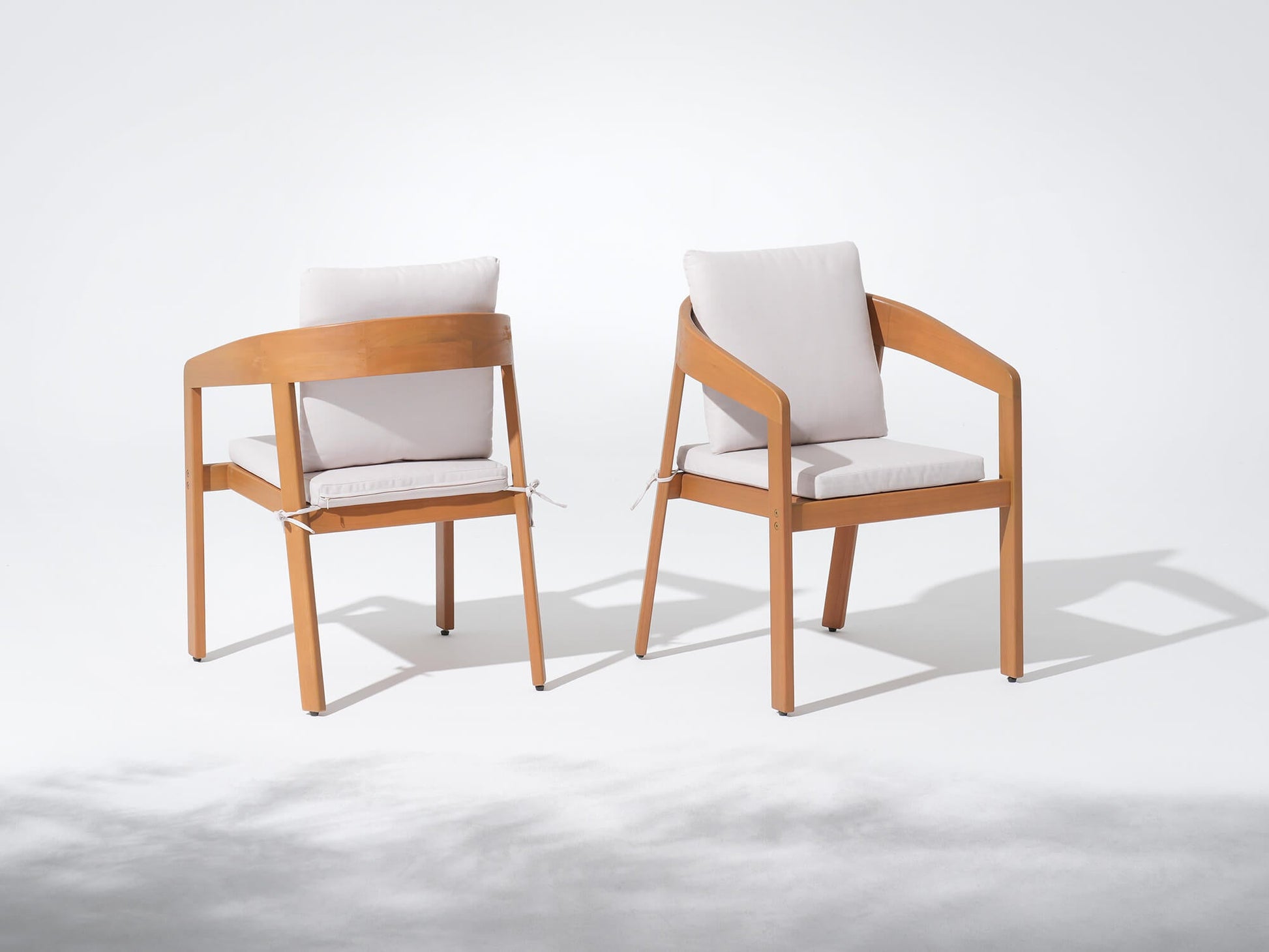 Two wooden chairs with white cushions on a white background, Drift Wooden Outdoor Dining Chairs With Curved Backrest - Sunsitt’s Modern Premium Outdoor Furniture