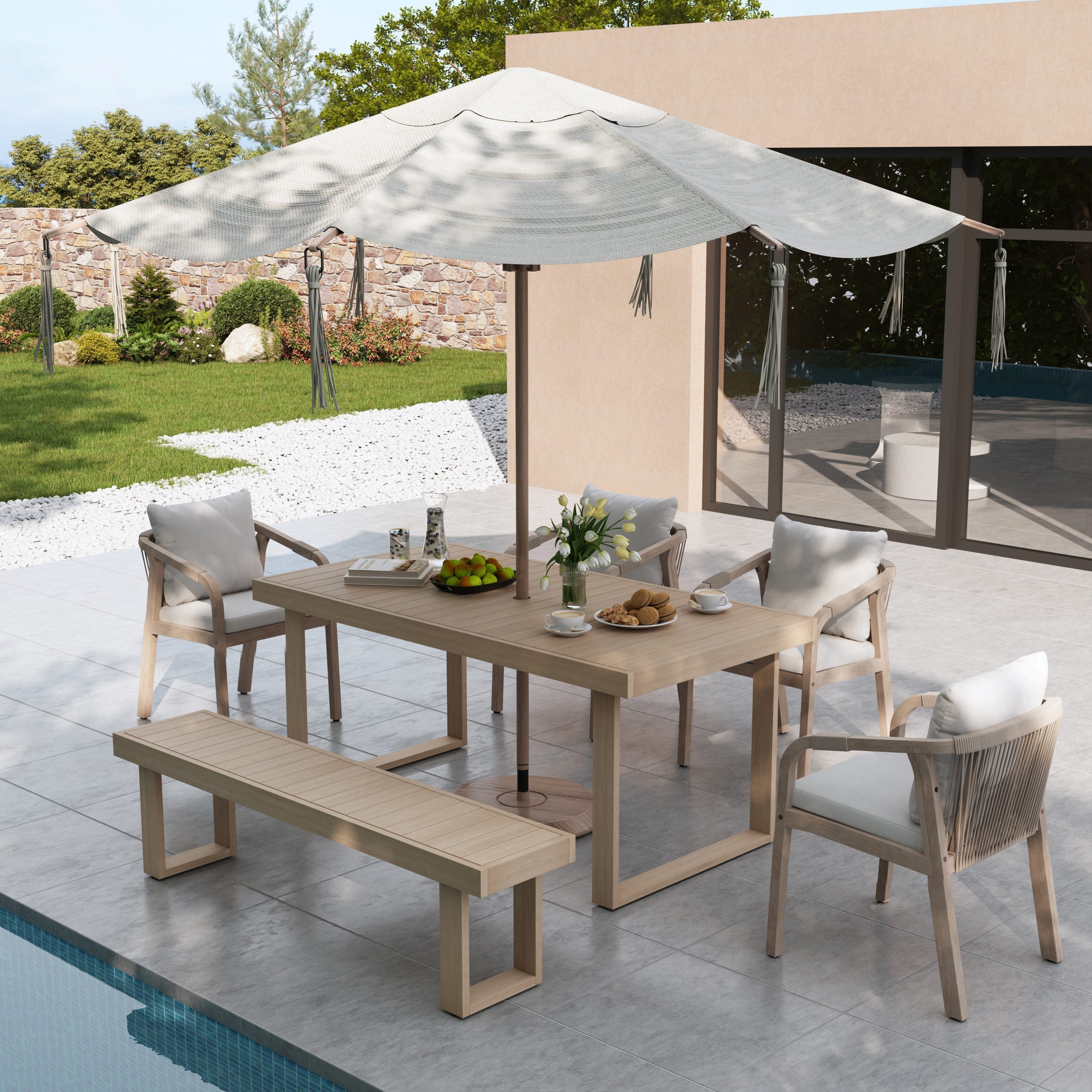 Outdoor dining set with table, chairs, and bench under a large umbrella by a pool.