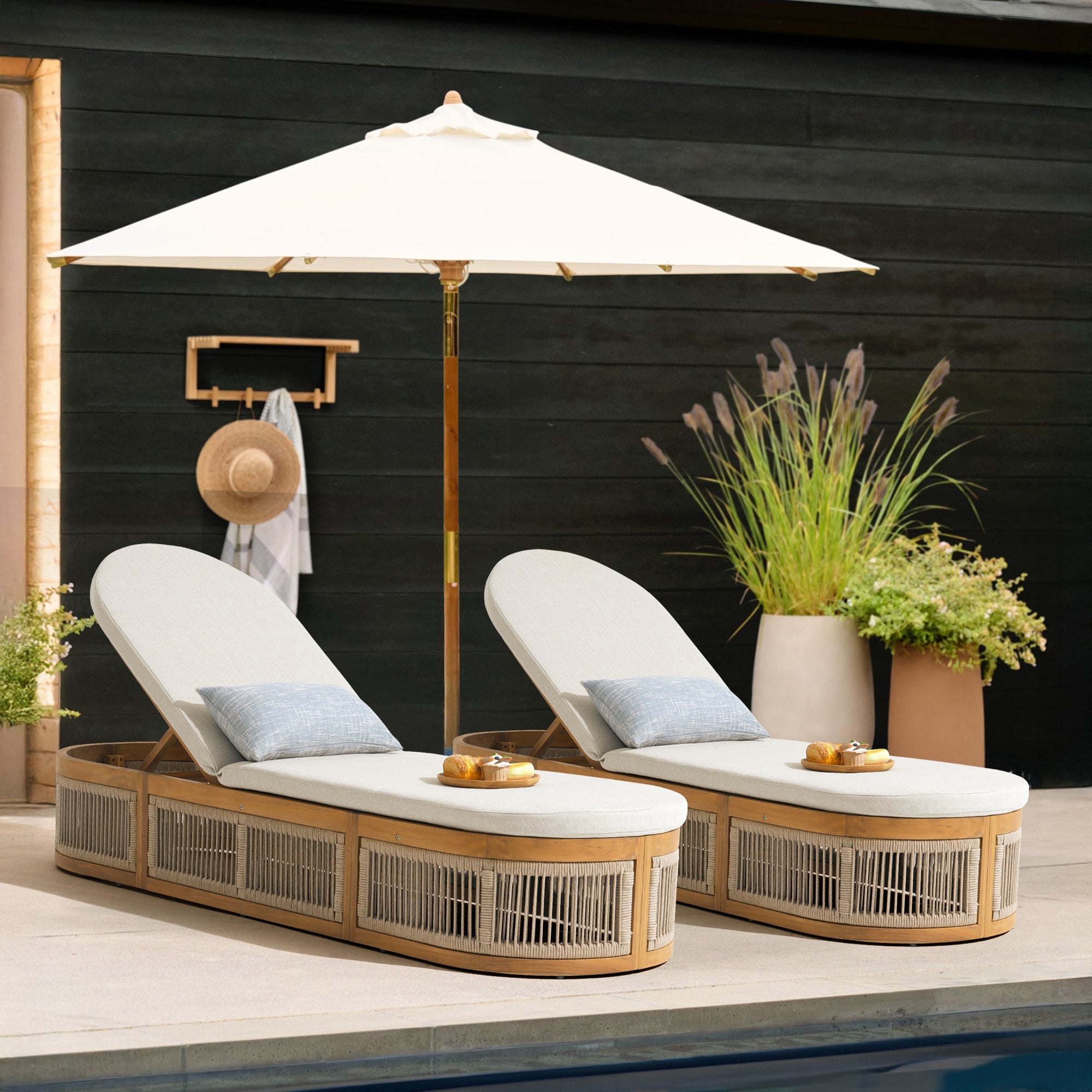 Two wood and rope lounge chairs under a large umbrella 