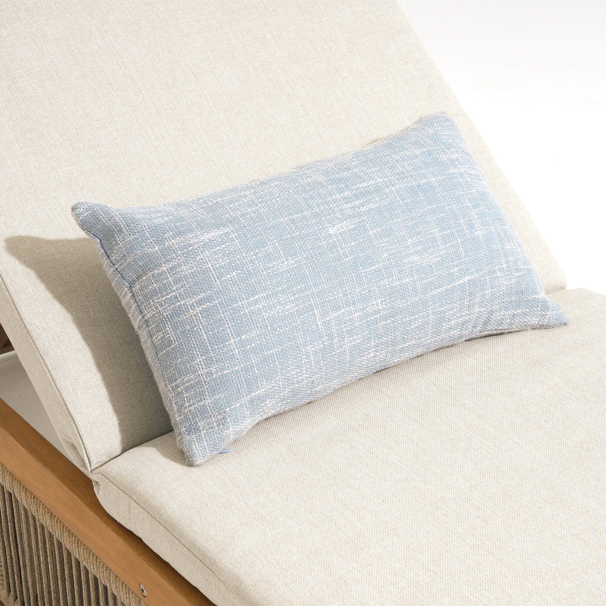 Blue textured pillow on a beige wood lounge chair