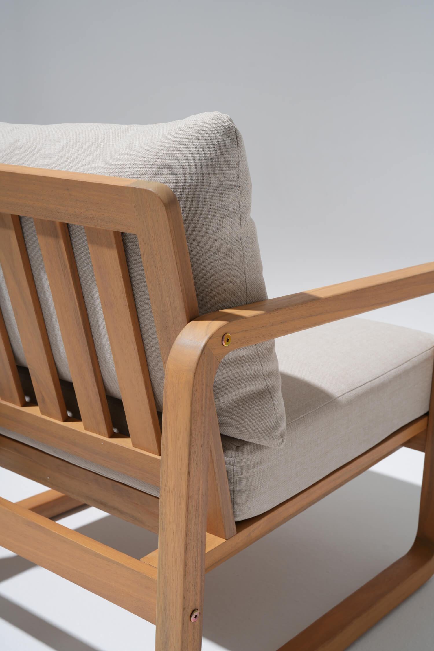 Wooden chair with beige cushions, armrest detail