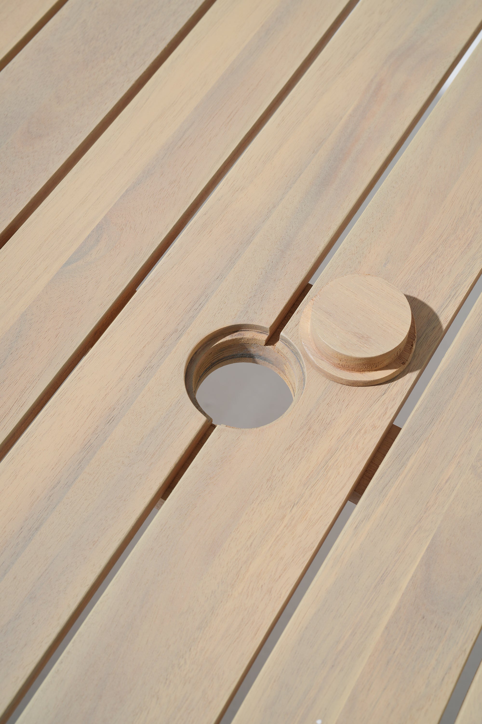Close-up of a wooden table with a circular umbrella hole 