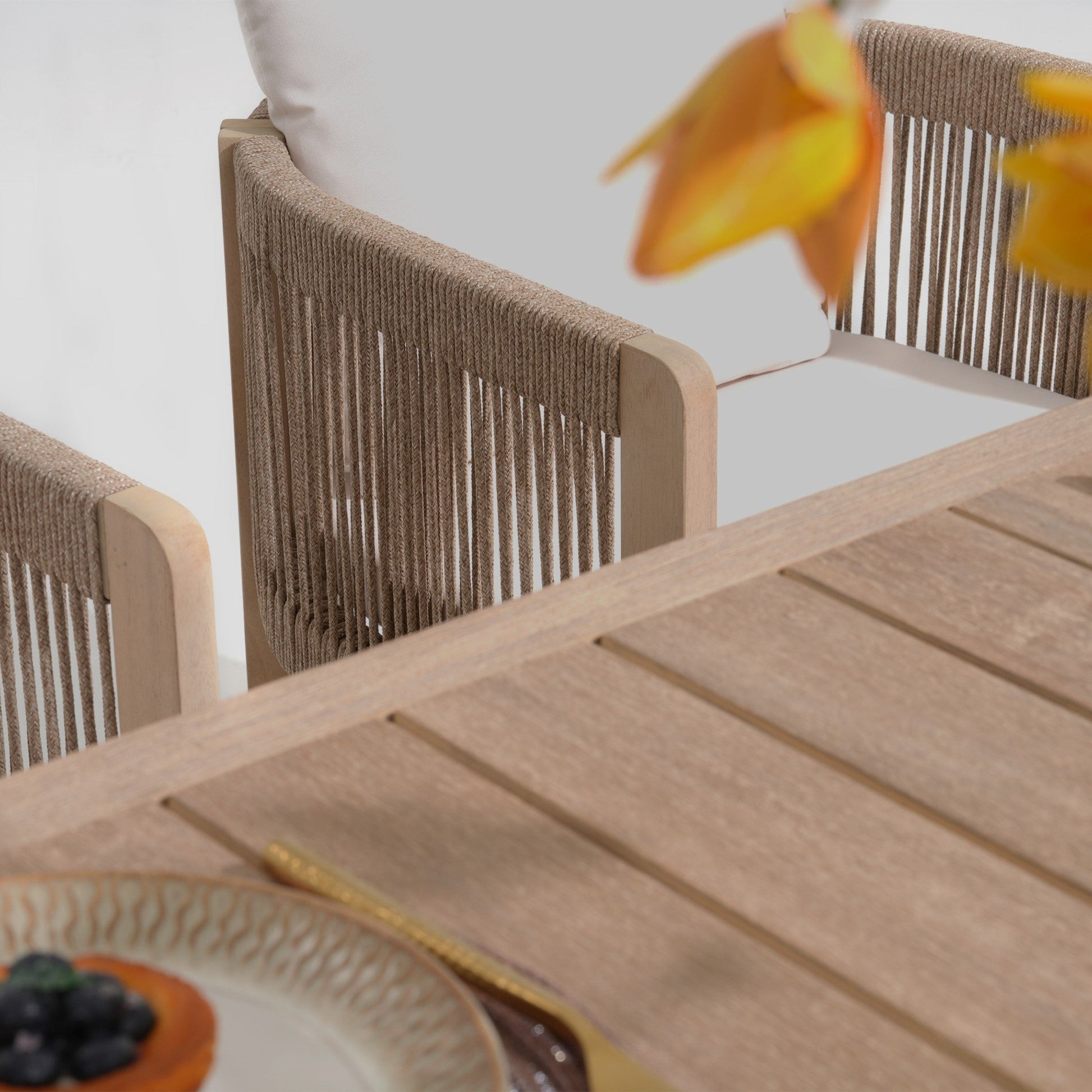 Wooden outdoor table with chairs and a blurred flowerrectnagular wood patio dining tabletop detail - Sunsitt Modern Premium Outdoor Patio Furniture